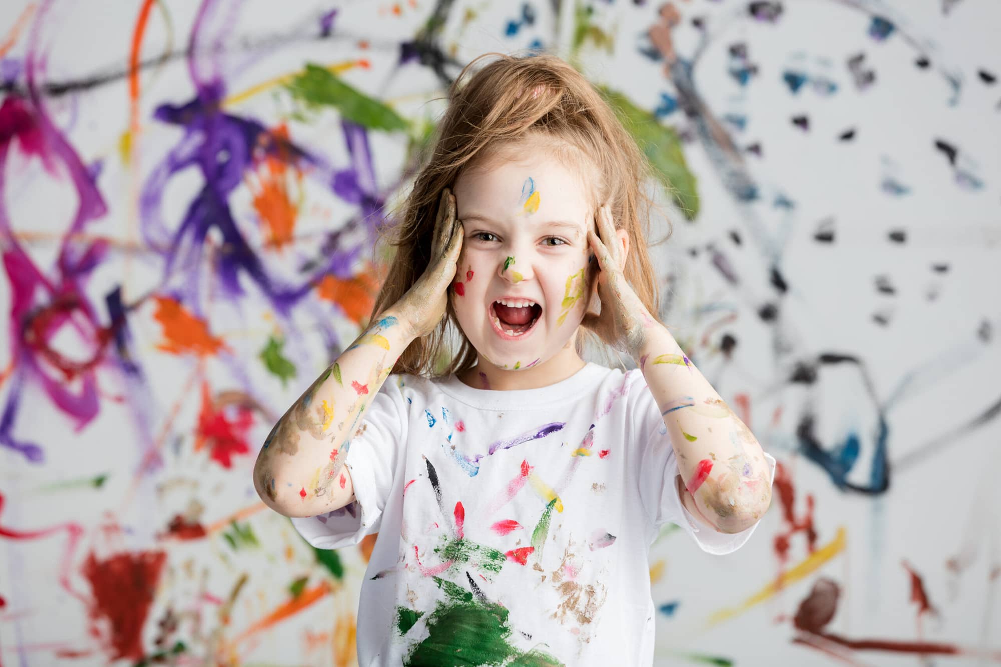 Shocked little girl grabbing her head, looking surprised. Messy fun. Shocking discovery.
