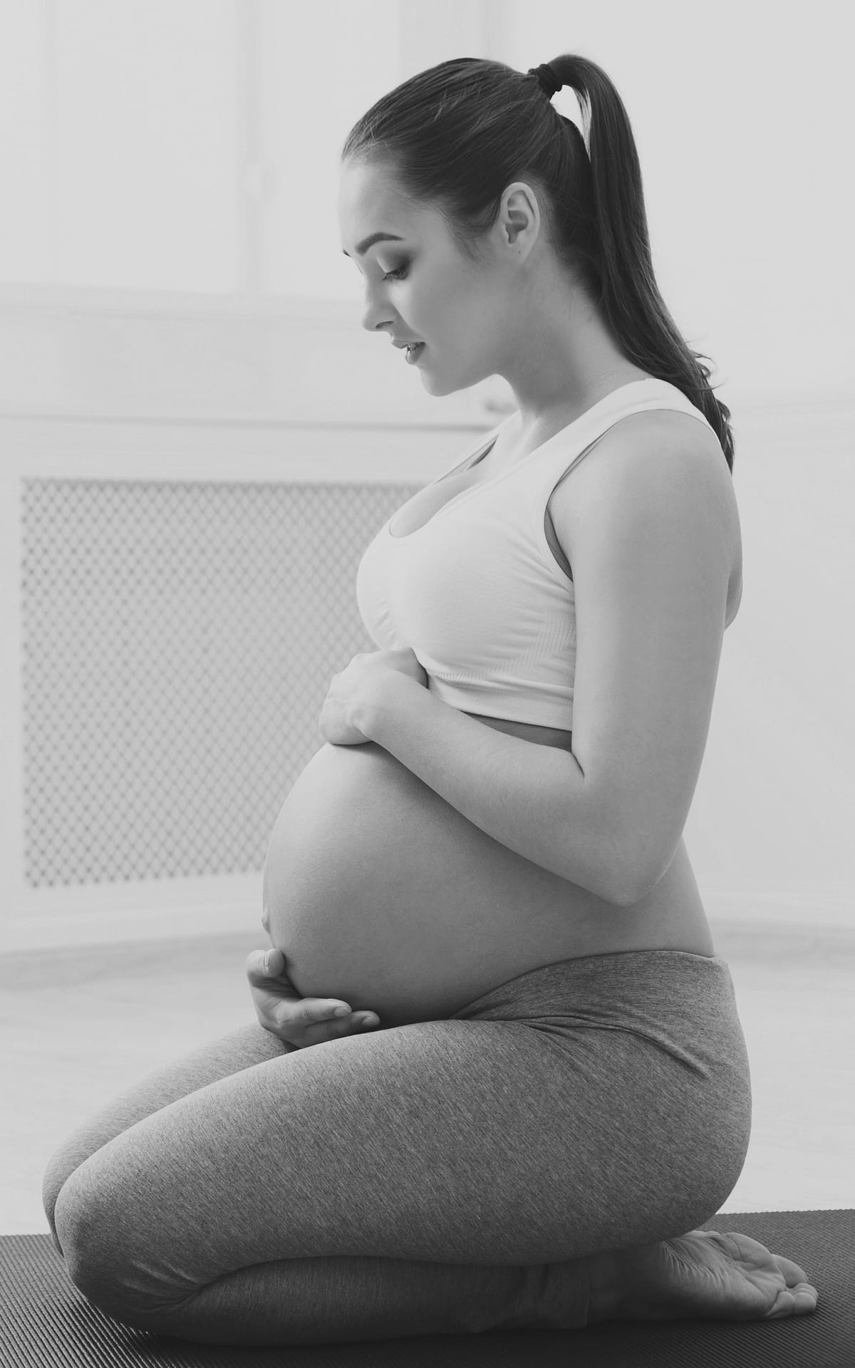Pregnant woman training yoga in lotus pose Pregnant woman training yoga in hero pose and caressing her belly. Young happy expectant relaxing, thinking about her baby and enjoying her future life. Motherhood, pregnancy, happiness, yoga concept